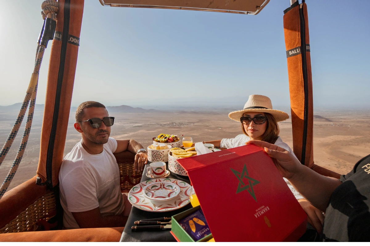 Couple souriant lors d’un vol en montgolfière à Marrakech, tenant une échographie – moment romantique inoubliable à deux