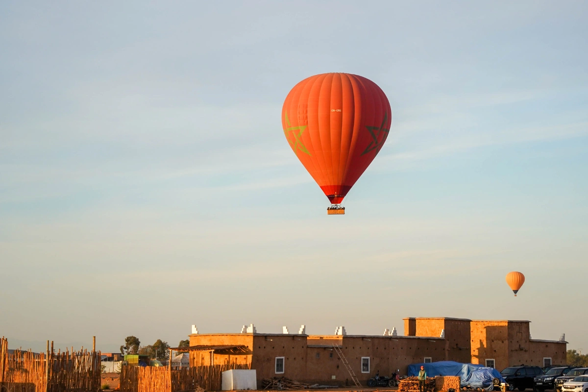 Vol en montgolfière Marrakech au lever du soleil, survolant les habitations et les paysages du désert marocain.