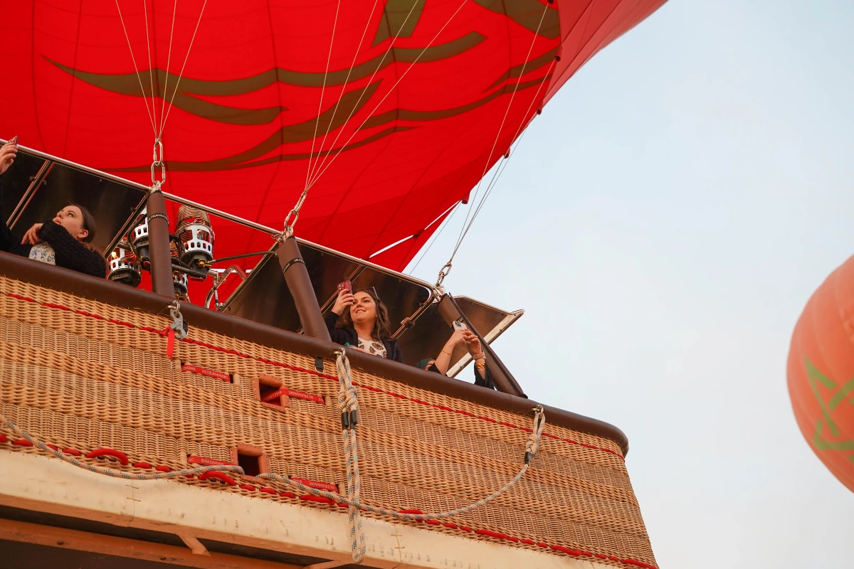 Passagère souriante prenant une photo lors d’un vol en montgolfière Marrakech au lever du soleil.